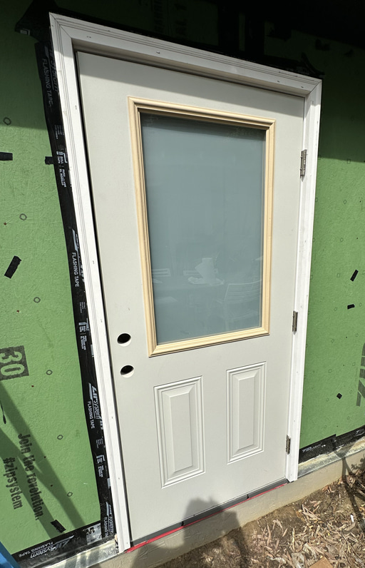 Installed outswing door with door glass.